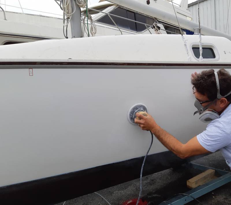 Lustrage et ponçage de la coque du bateau avant application de stickers personnalisés